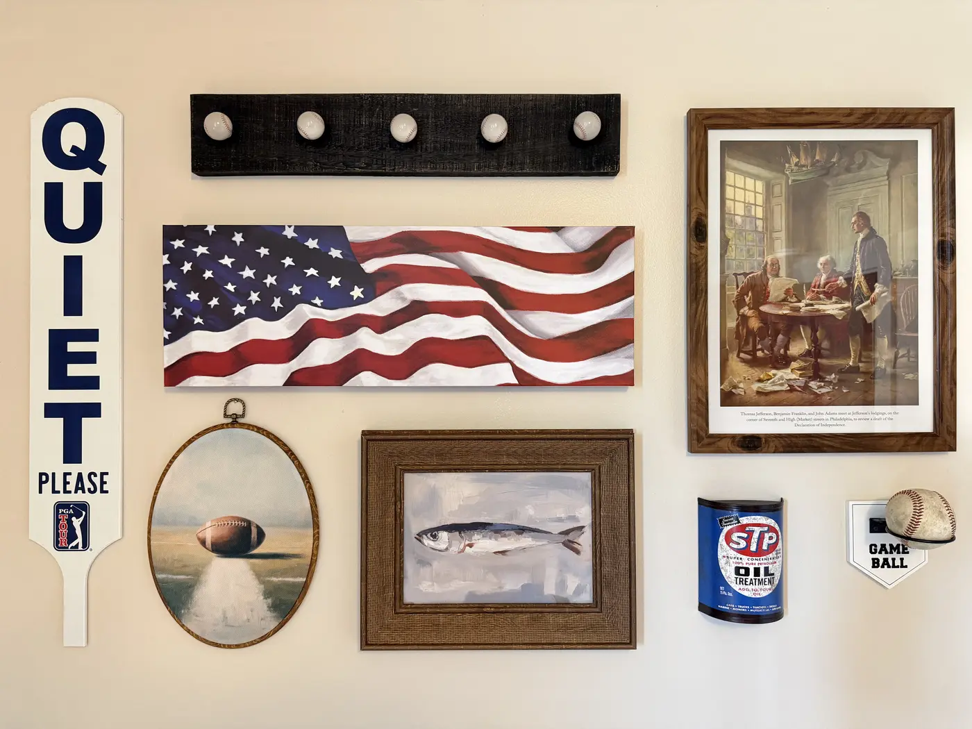 Curated wall display featuring baseballs, vintage sports pieces, an American flag painting, and regional artwork